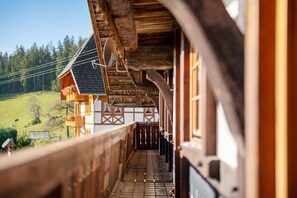 A wooden balcony with a view of a house and a green landscape. - Holiday Apartment 'Bauernhaus' with Balcony and Wi-Fi (Hornberg)