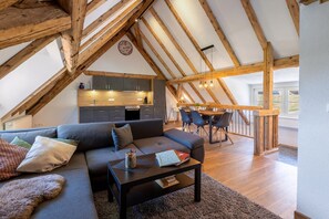 Un espace de vie de style loft comprenant un coin repas, des poutres en bois et une cuisine.