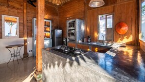 Eine rustikale Küche mit Holzwänden, einer zentralen Kochinsel mit Herd, Kühlschrank und Mikrowelle.