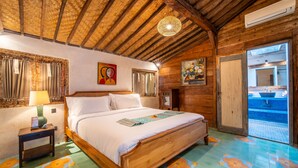 Ein schlicht eingerichtetes Schlafzimmer mit Holzbett, Nachttisch, einem Fenster mit Vorhängen und Blick auf einen Pool durch eine offene Tür.