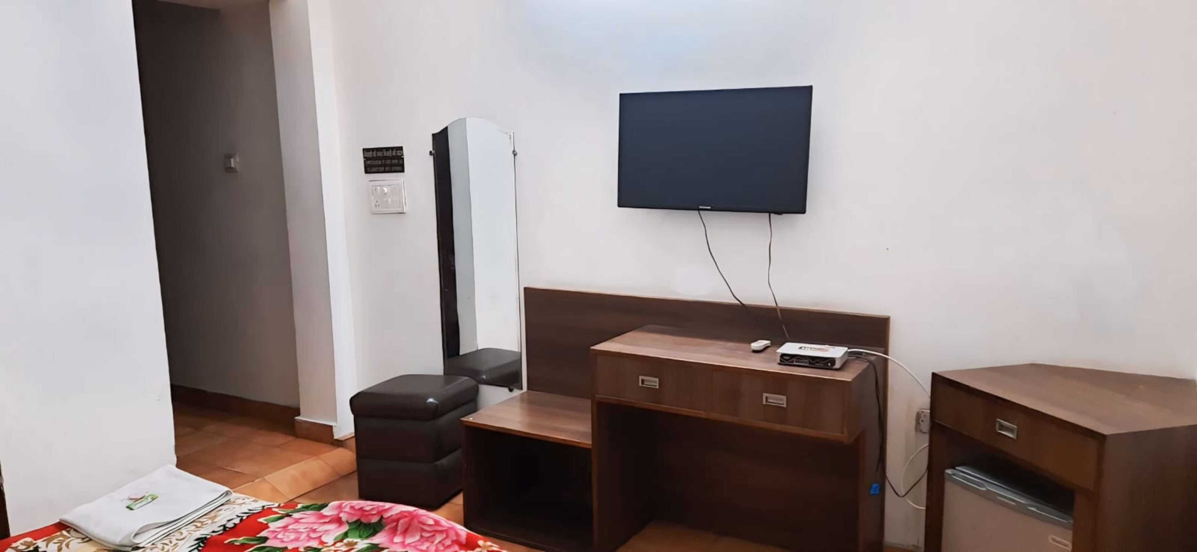 Una habitación de hotel con cama, escritorio, silla, televisión y armario.