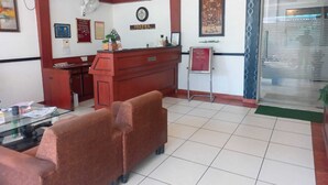 A hotel reception area with a reception desk, a sofa, a glass table, and a framed welcome sign. - Hotel Sagar By GRB (Meerut)
