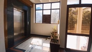 A hallway with a marble floor, a potted plant, and a window with a view of the outside. - Hotel Sagar By GRB (Meerut)