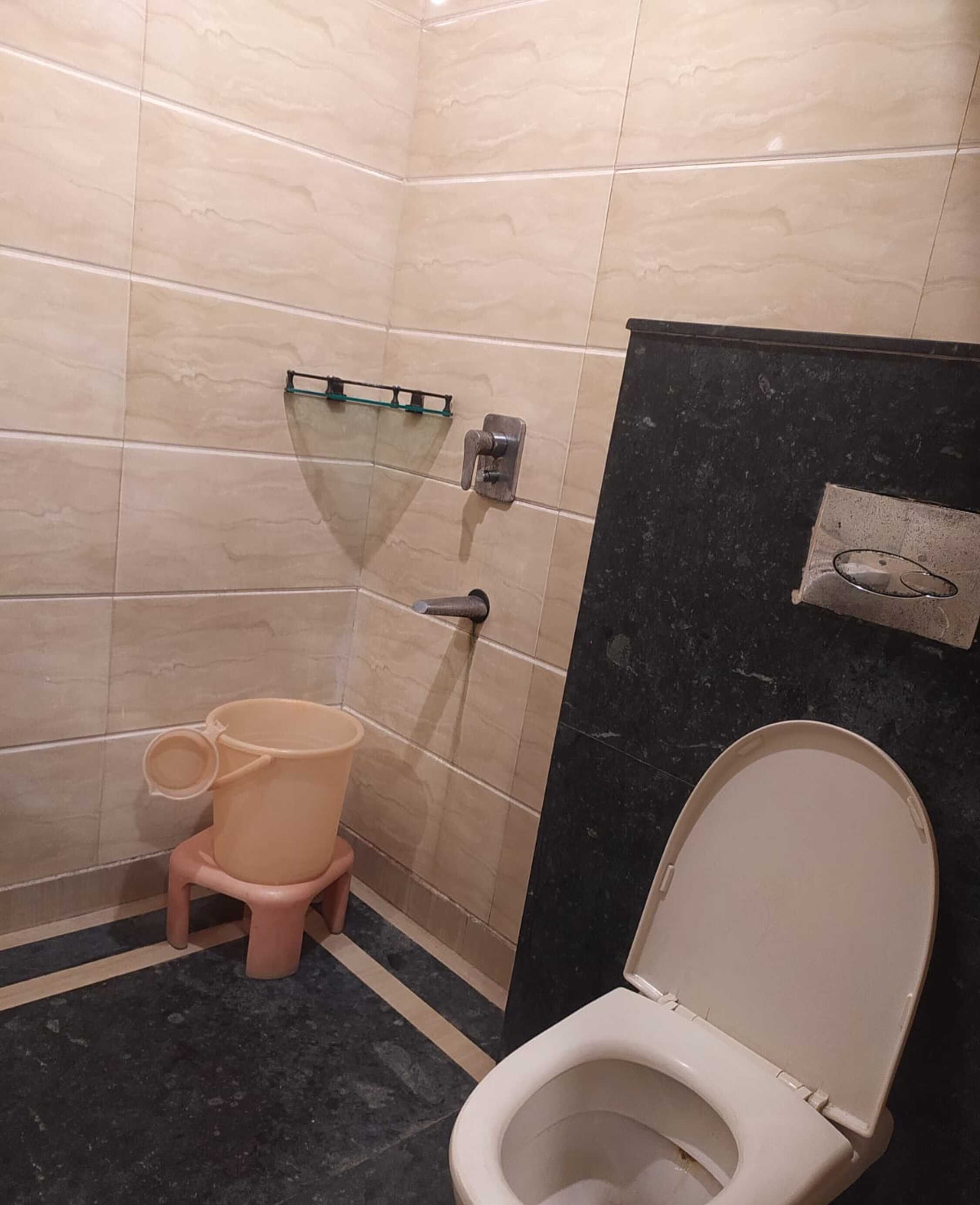 Ein kleines Badezimmer mit Toilette, Mülleimer und Duschbereich.