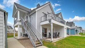 Kaksikerroksinen talo, jossa on katettu kuisti ja portaat, jotka johtavat yläkertaan.
