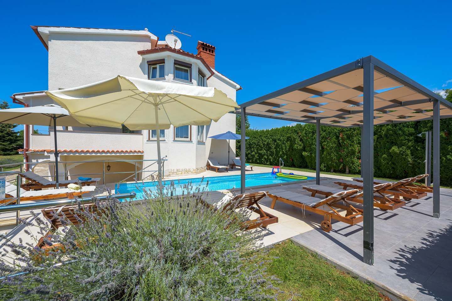 A modern house with a swimming pool, outdoor seating, and a covered patio area.