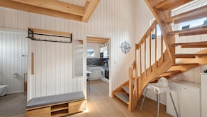 Et moderne interiør med en trætrappe, en bænk og et køkkenområde.