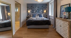 Relax in a stylish room with a central bed, large mirror, and wooden console table.