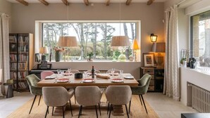 A dining area with a wooden table set for four, surrounded by chairs. A piano and bookshelf are visible in the background. - Ker Lan - Character house with Spa and sea view (Lanildut)