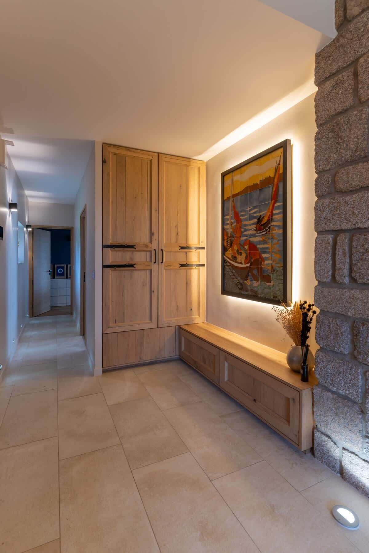 A modern interior with a wooden bench, a stone accent wall, and a framed painting.