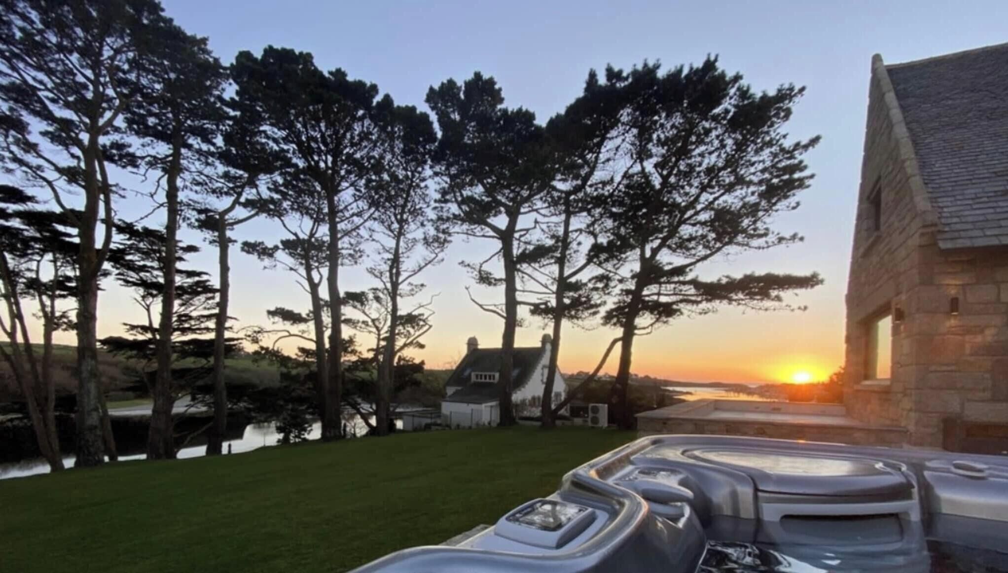 A serene lakeside property with a stone building, a grassy lawn, and trees.