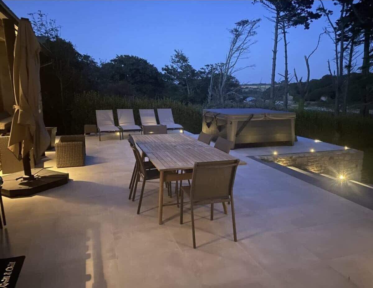 Ein Außenbereich mit einer Essgruppe, einer überdachten Lounge-Ecke und einem kleinen Pool.