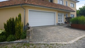 Ein zweistöckiges Haus mit Ziegeldach, einer Garage und einem gepflasterten Auffahrt.