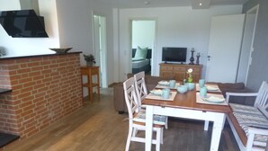 Ein Essbereich mit Backsteinwand, Holzboden und einem Esstisch, gedeckt mit Tellern, Schüsseln und Tassen.
