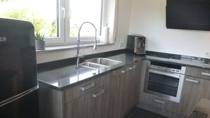 Eine moderne Küche mit einem Edelstahl-Kühlschrank, einer Spüle mit zwei Becken, einem Einbauofen und einer Mikrowelle.