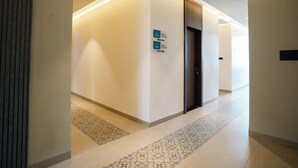 Un couloir d’hôtel moderne, avec des panneaux indicateurs indiquant les chambres 201 à 204 et les chambres 205 à 208.