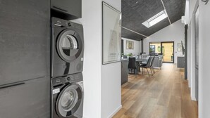 A modern kitchen with built-in appliances, a dining area with a table and chairs, and a view of the living room through an open door.
