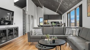 A modern living room with a grey sectional sofa, a coffee table, and a TV.