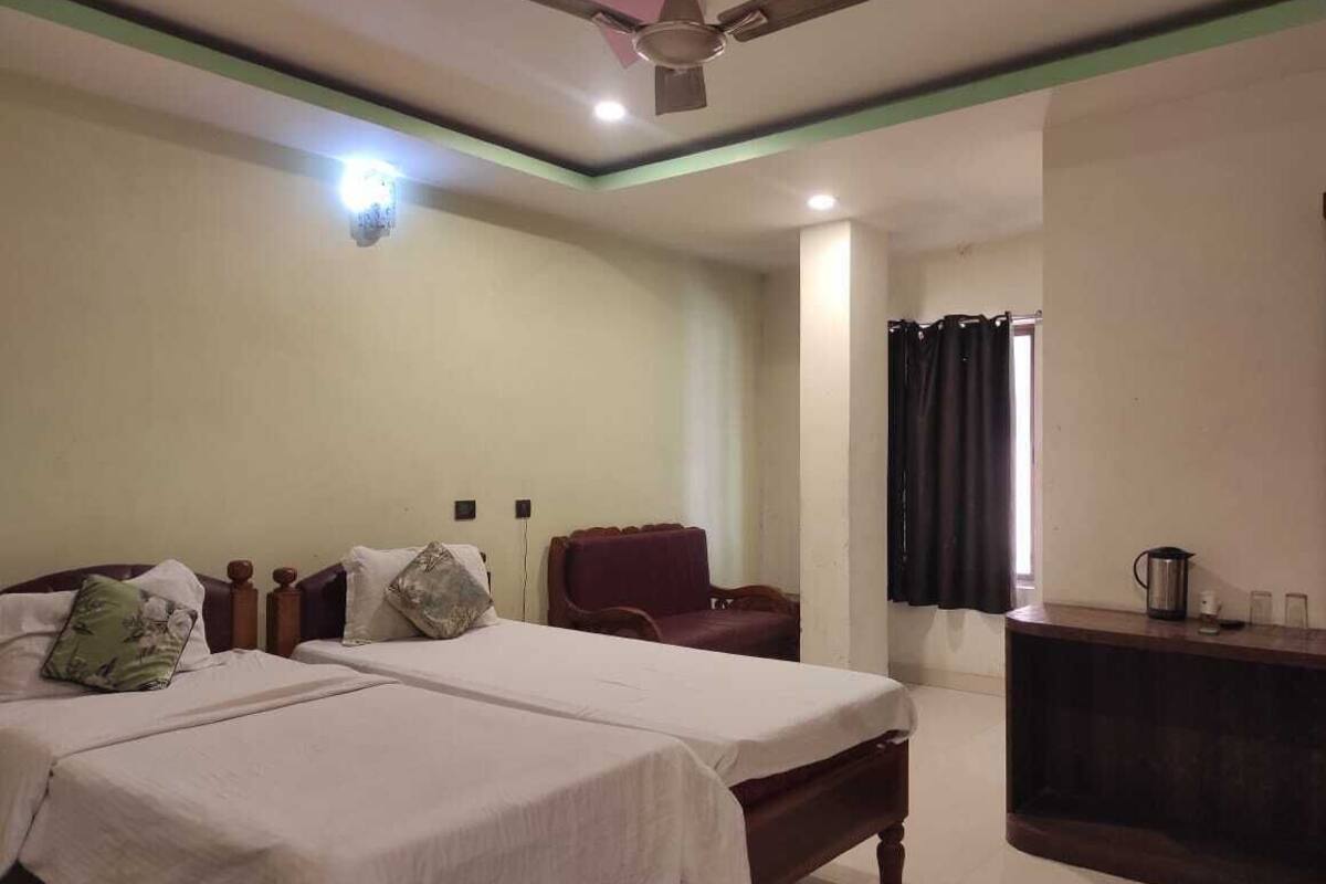 A bedroom with two beds, a desk, a chair, and a ceiling fan.