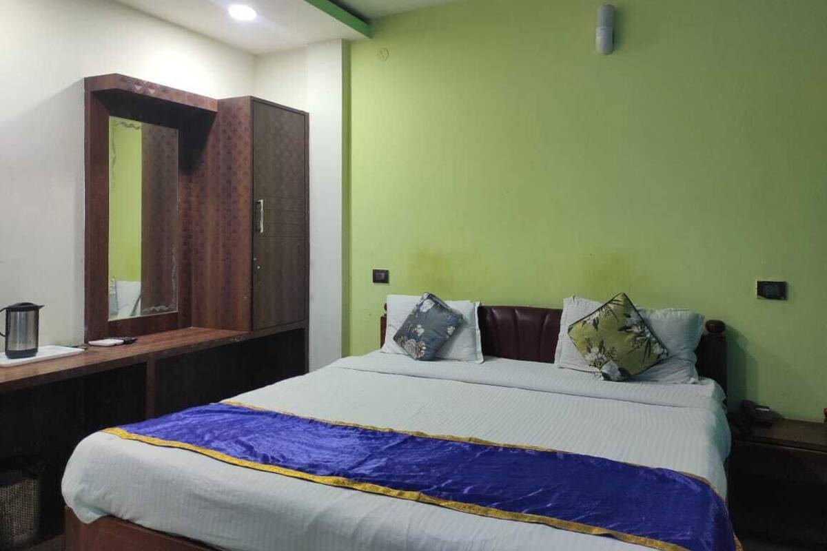 A bedroom with a bed, a wardrobe, a desk, and a green wall.