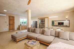 A modern living room with a sectional sofa, wooden coffee table, and a TV mounted on the wall. - Private Pool Villa Kokos (Kiwengwa)