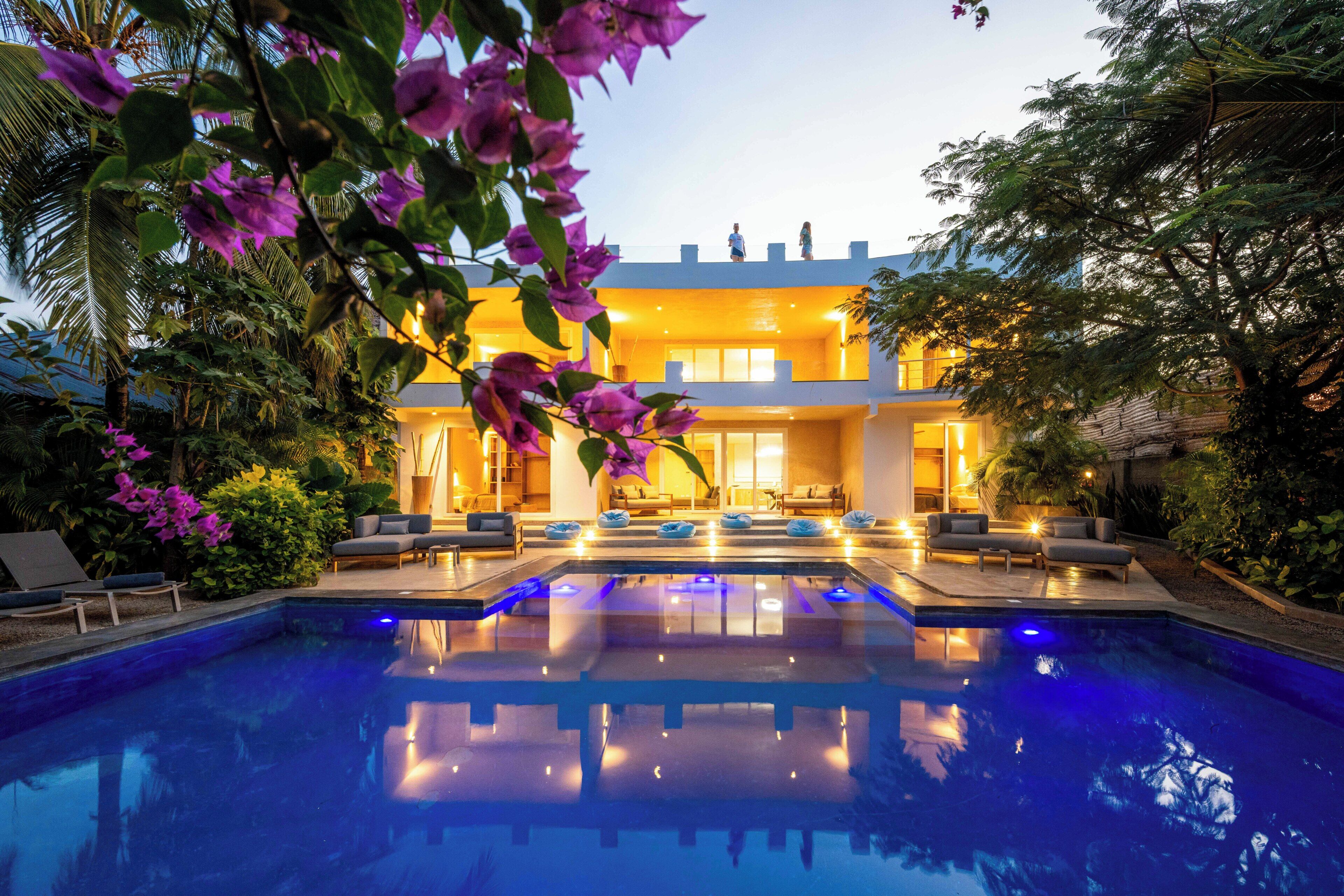 A pool with lounge chairs and a building with a balcony.