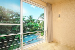A room with a large window overlooking a swimming pool and lush greenery.