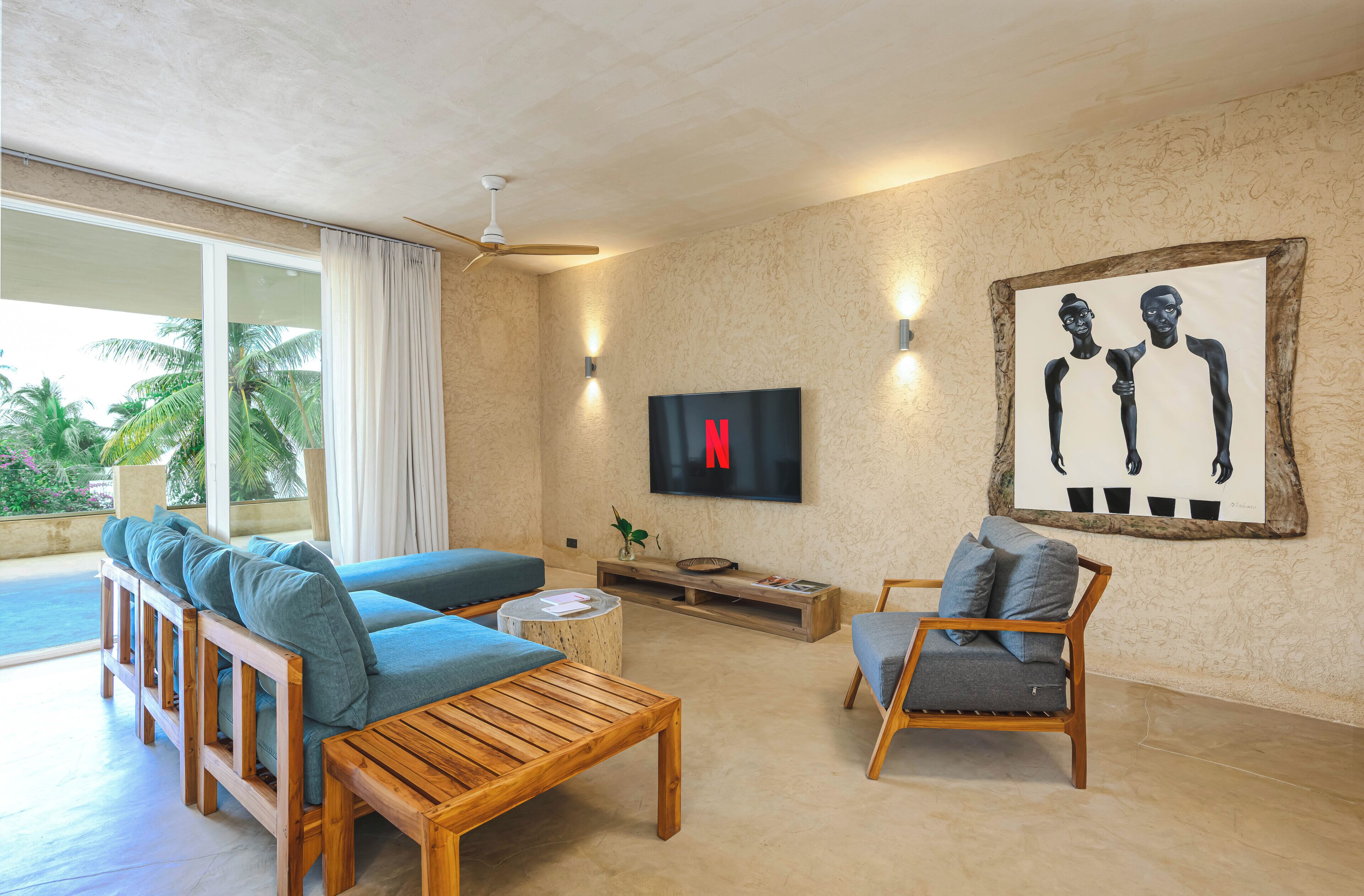 A modern living room with a sofa, a wooden coffee table, a TV mounted on the wall, and a painting.