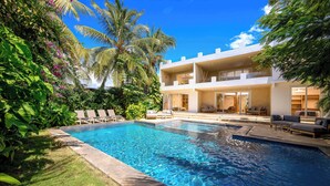 A modern two-story building with a swimming pool, lounge chairs, and a well-maintained garden. - Private Pool Villa Kokos (Kiwengwa)