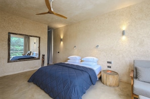 A bedroom with a bed, a ceiling fan, a mirror, and a bedside table.