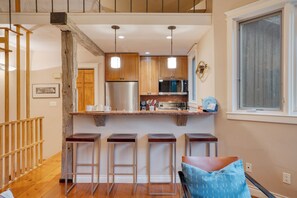 A modern kitchen with wooden cabinets, stainless steel appliances, and a bar area with stools.