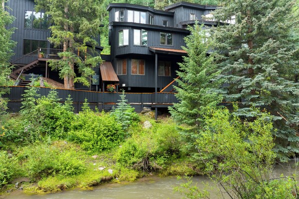 A modern multi-story building with a wooden deck and stairs leading to the entrance.