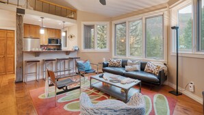 A spacious living area with a sofa, coffee table, and a dining area with bar stools. - Manitou River House 113 by AvantStay | A+ Location (Telluride)