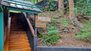 A wooden staircase leading to a building labeled "Manitou Riverhouses" with directional signs for room numbers 101-108 and 109-119. - Manitou River House 113 by AvantStay | A+ Location (Telluride)