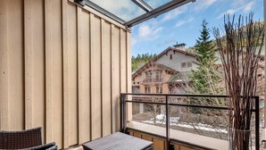 A room with a wooden wall and a large window overlooking a snowy landscape and a building. - Lake Placid Lodge Loft 2 bedroom (Whistler)