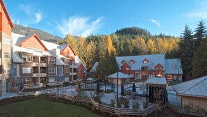 A resort with multiple buildings, outdoor seating areas, and a mountainous backdrop. - Lake Placid Lodge Loft 2 bedroom (Whistler)