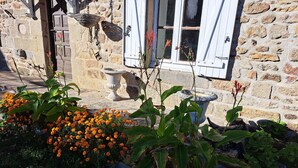 A stone building with a rustic charm, featuring a stone wall, a wooden door, and a window with shutters. - Maison de Campagne Proche Monts D'ambazac et Limoges (La Jonchère-Saint-Maurice)