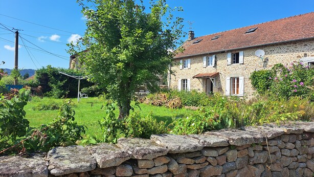 A stone house with a tiled roof, surrounded by a stone wall and lush greenery. - Maison de Campagne Proche Monts D'ambazac et Limoges (La Jonchère-Saint-Maurice)