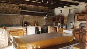 A kitchen with a bench, a refrigerator, a microwave, and a clock on the wall. - Maison de Campagne Proche Monts D'ambazac et Limoges (La Jonchère-Saint-Maurice)