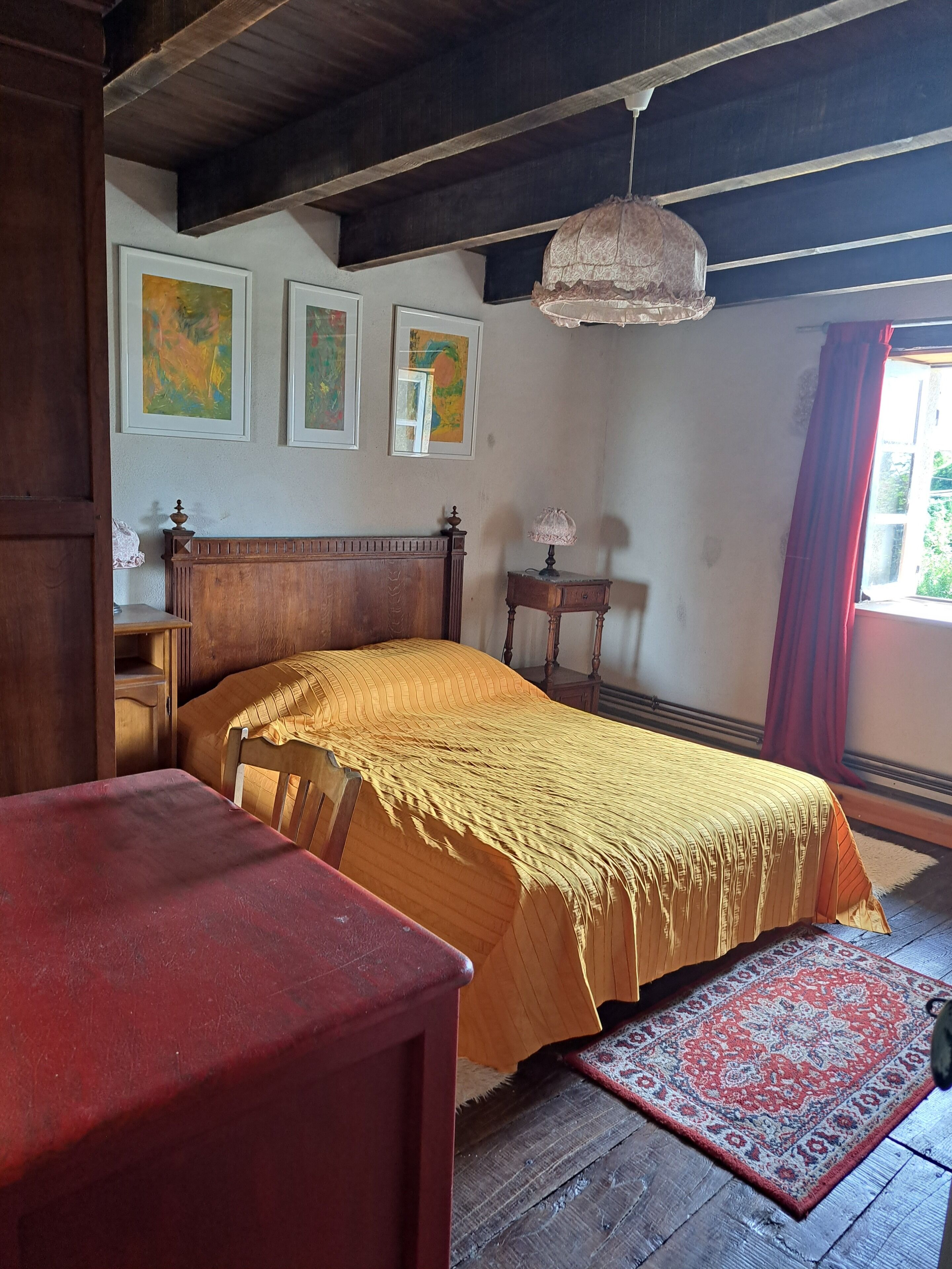 A bedroom with a wooden bed, a nightstand, a lamp, and a rug.