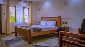 Une chambre avec un lit simple, une tête de lit en bois, une table de chevet et une chaise.