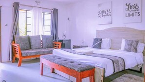 A bedroom with a bed, a bench, a sofa, and a chair. There are curtains on the windows. - Riverside Villas Nanyuki  (Nanyuki)