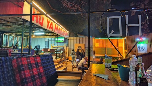 An indoor bar area with a wooden bar, seating, and a dartboard. - Riverside Villas Nanyuki  (Nanyuki)