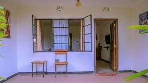 A room with a large window, a wooden bench, and a door leading to another room. - Riverside Villas Nanyuki  (Nanyuki)