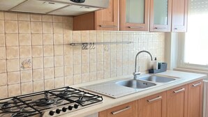 Une cuisine avec des meubles de rangement en bois, une cuisinière à gaz, un évier et une fenêtre.