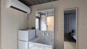Una kitchenette compacta con estufa integrada, lavamanos y espejo.