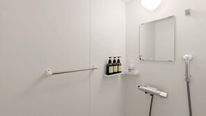Une salle de bain moderne avec une porte blanche, un porte-serviettes, une étagère contenant des articles de toilette, un miroir et une pomme de douche.