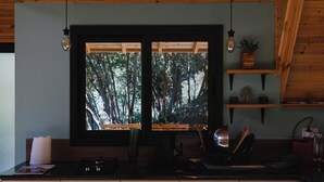 Een moderne keuken met houten kastjes, een groot raam en uitzicht op bomen.