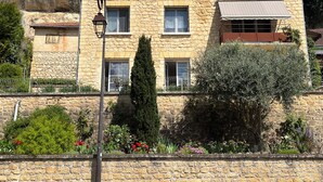 Un bâtiment en pierre doté d’un balcon, d’une cheminée et d’une fenêtre avec un rideau.