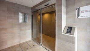 A modern elevator with a glass door, a wall-mounted information panel, and a control panel on the wall. - SeRENO Shinmachi 801 (Osaka)